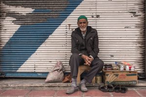elderly afghan male sitting before a wall